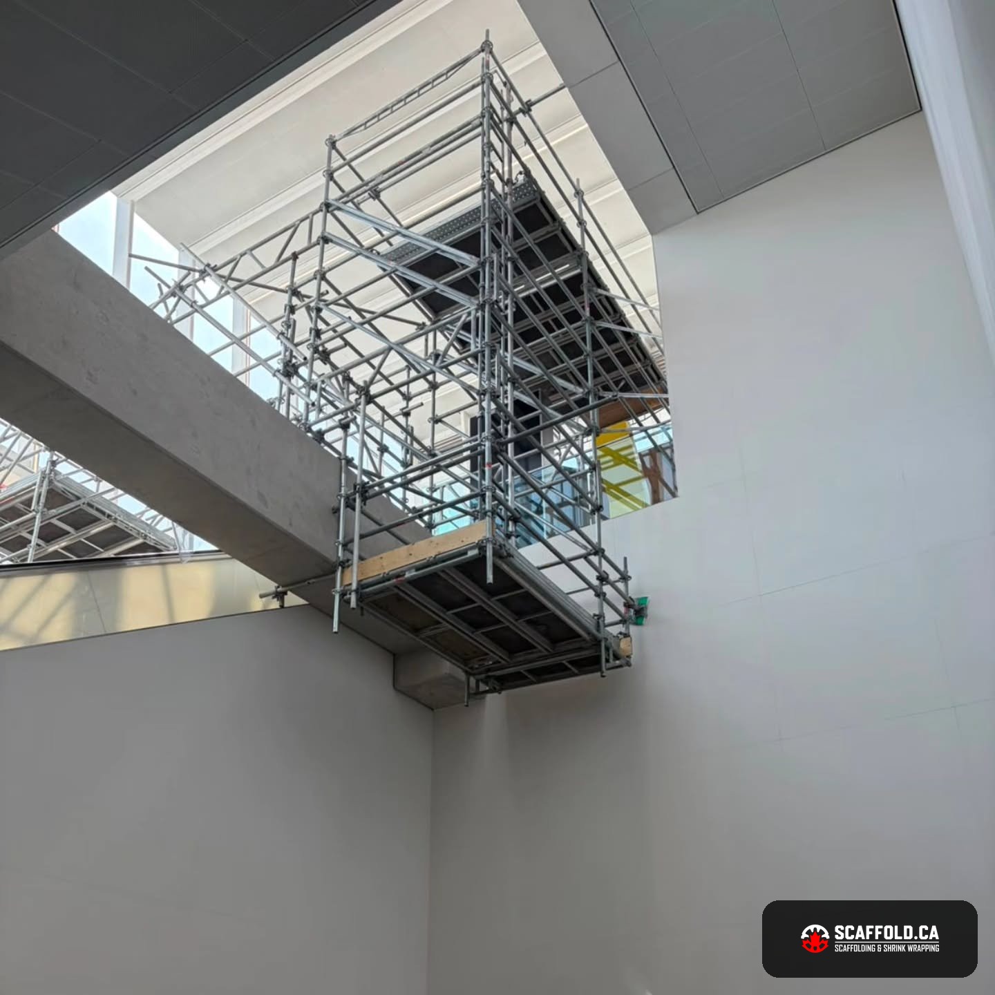 Cantilevered suspended scaffold spanning a live atrium
